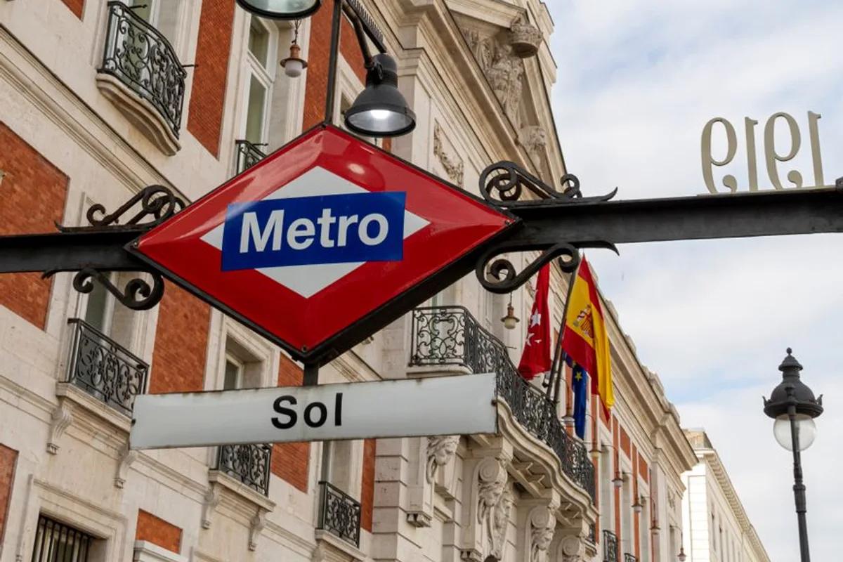 The Madrid Metro sign for Sol station, with the Real Casa de Correos building behind it