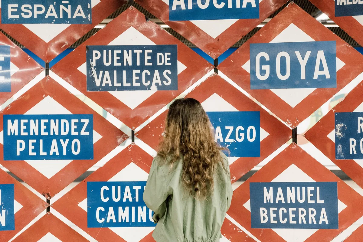 A visitor looks at a Madrid station-name display board with "Puente de Vallecas" among the tiles